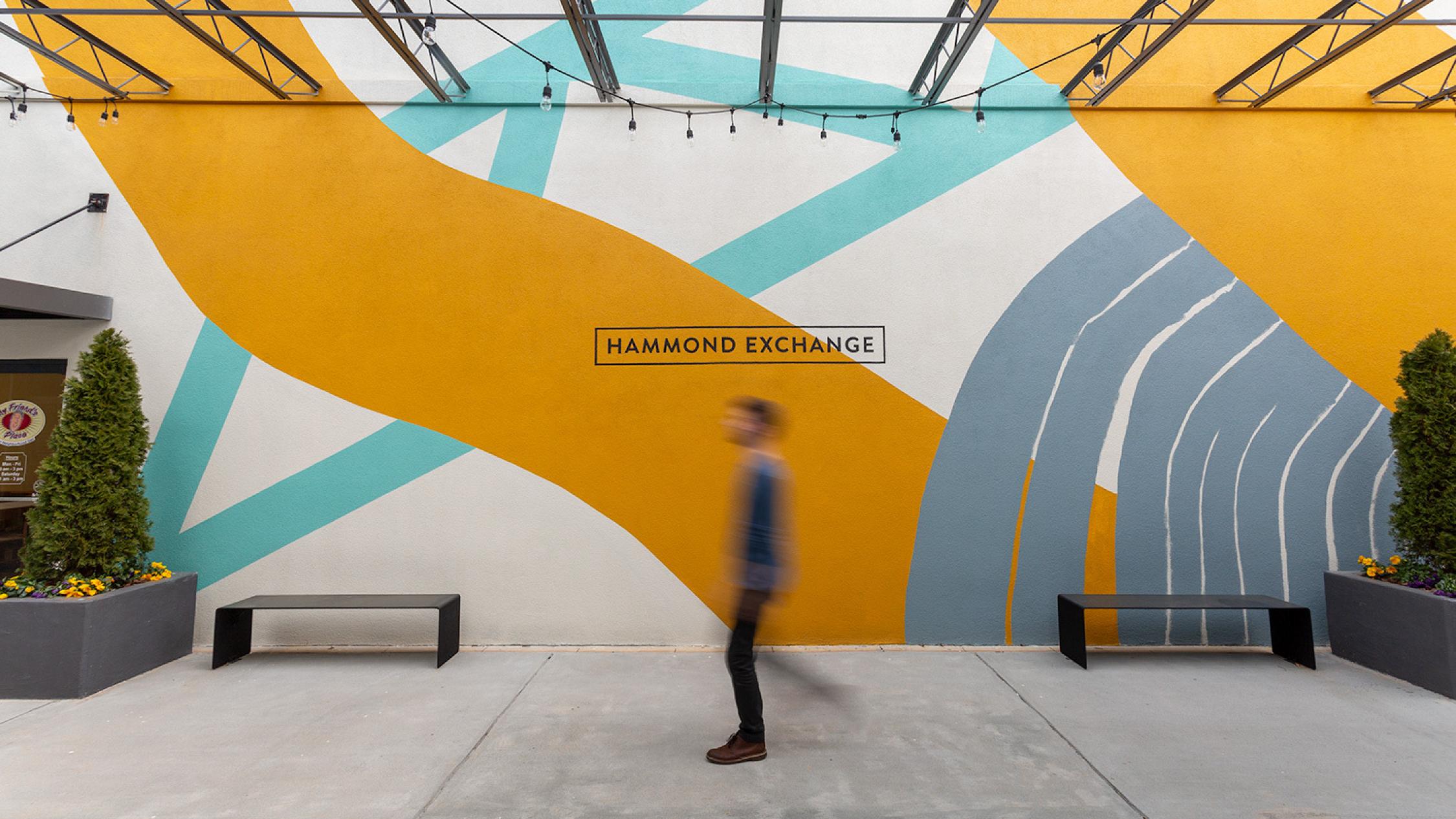 Pedestrian on sidewalk in front of mural artwork at Hammond Exchange