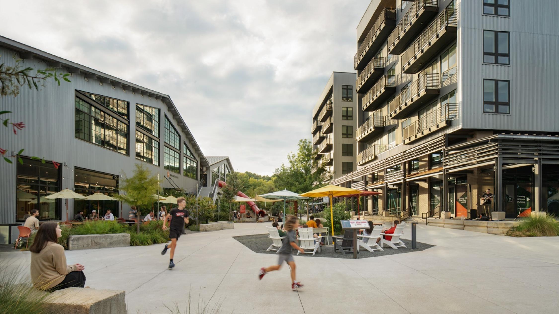 Exterior courtyard with visitors sitting and walking at Raleigh Iron Works
