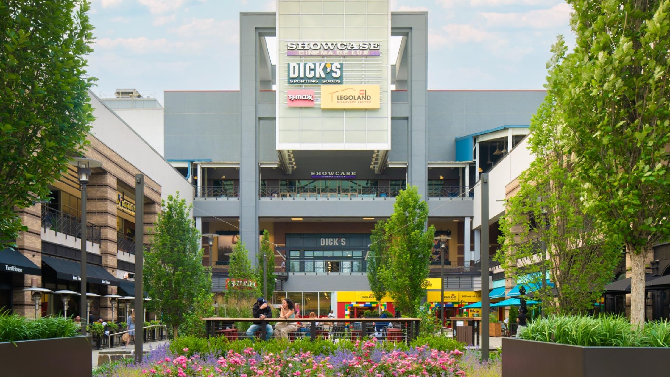 Visitors sitting in and walking through an exterior courtyard surrounded by shops at Ridge Hill