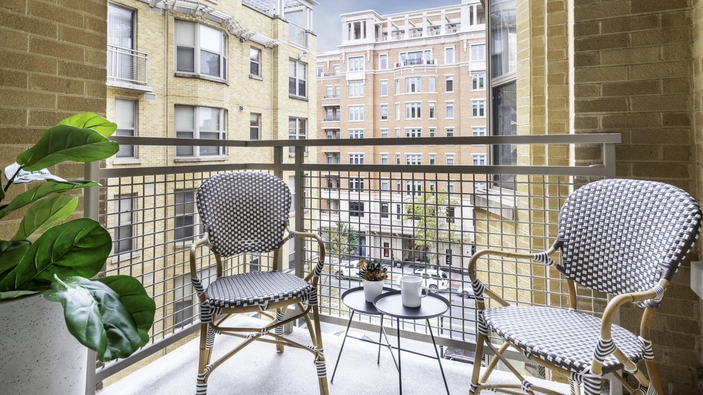 Patio of a model apartment at The Ellington with two chair and a blue sky in the distance