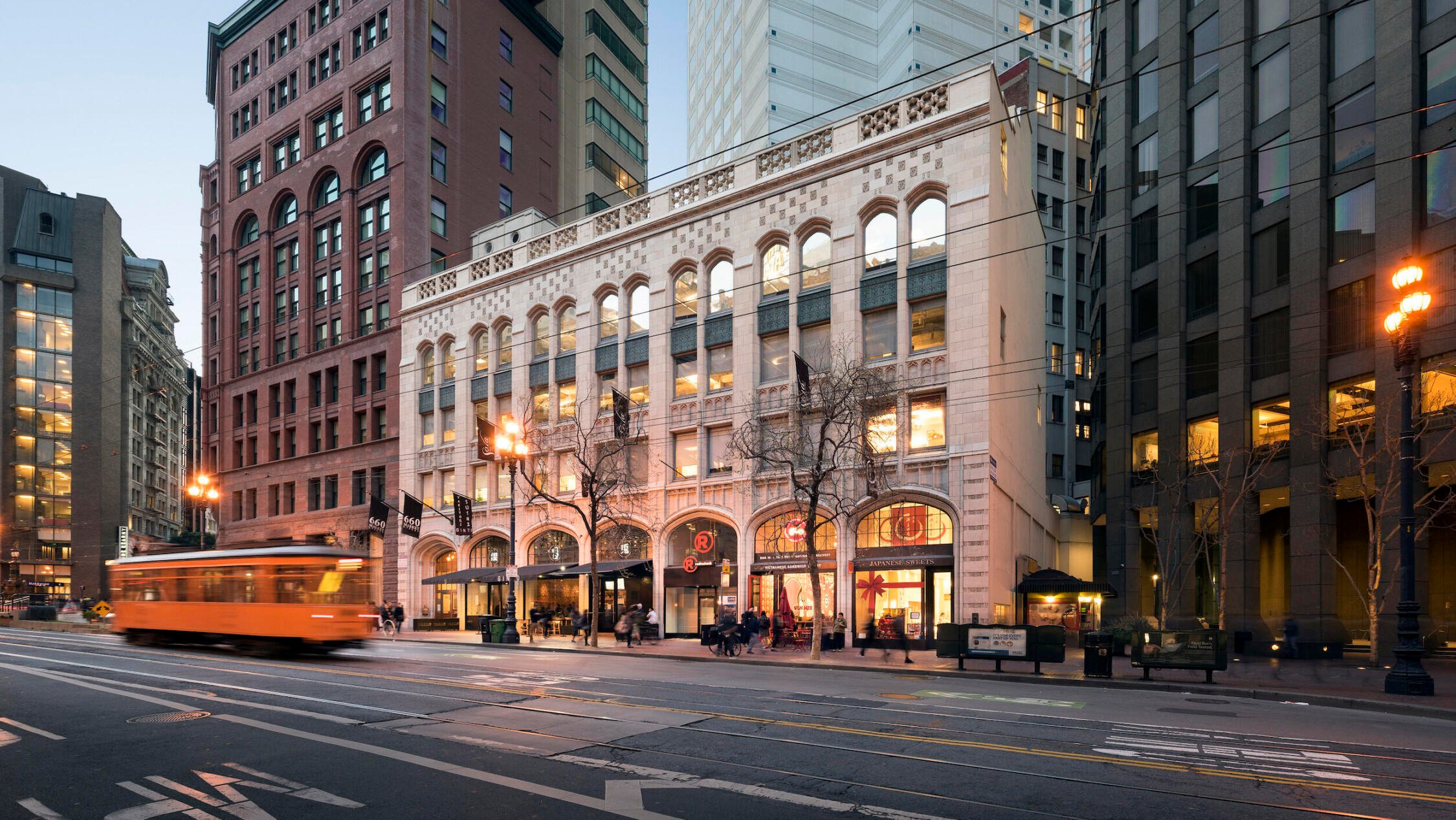 660 Market building facade at dusk with streetcar in midground and highrises in background