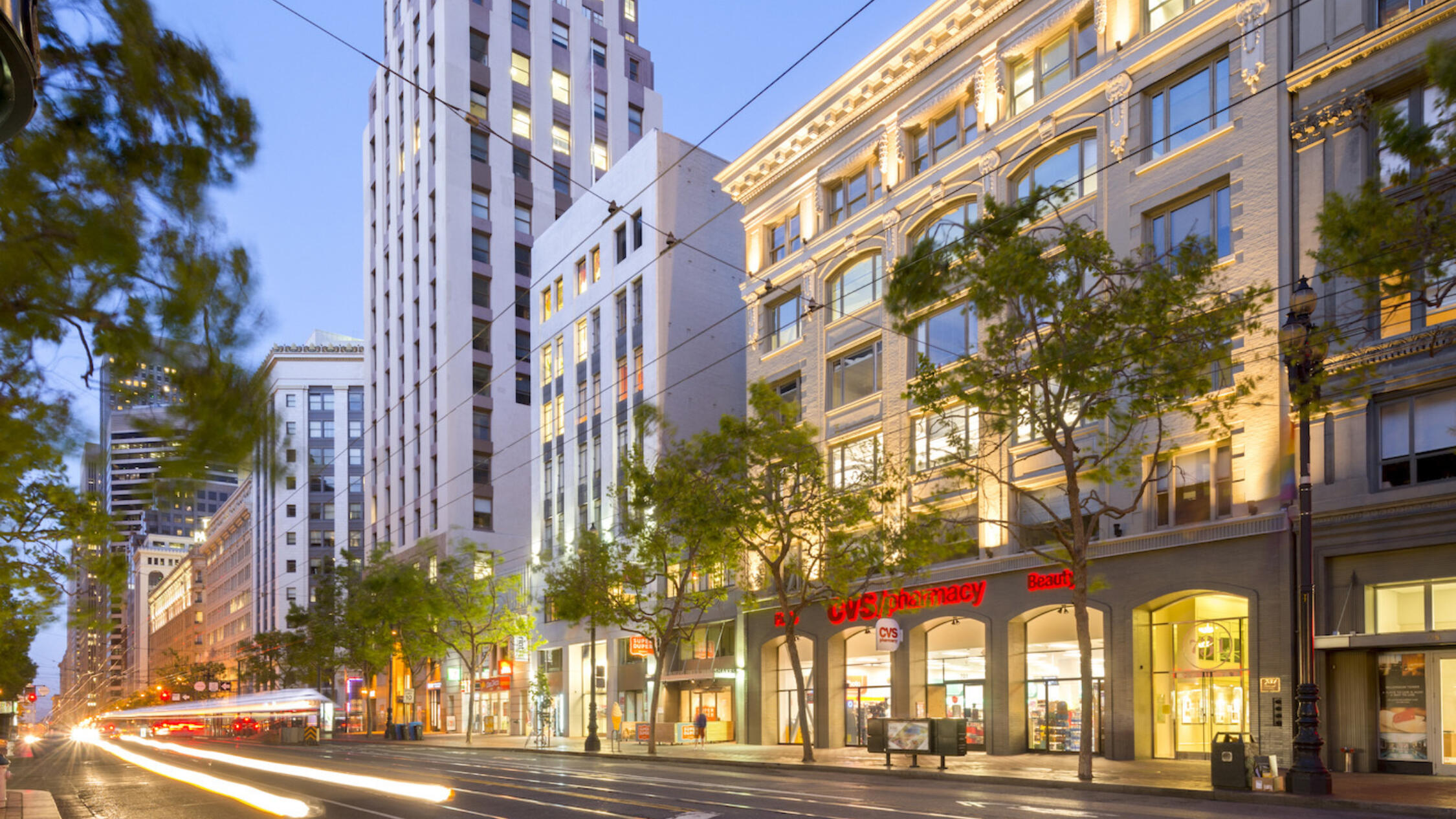 731 Market facade at dusk with motion blurred car headlights streaking down street and high rises in background