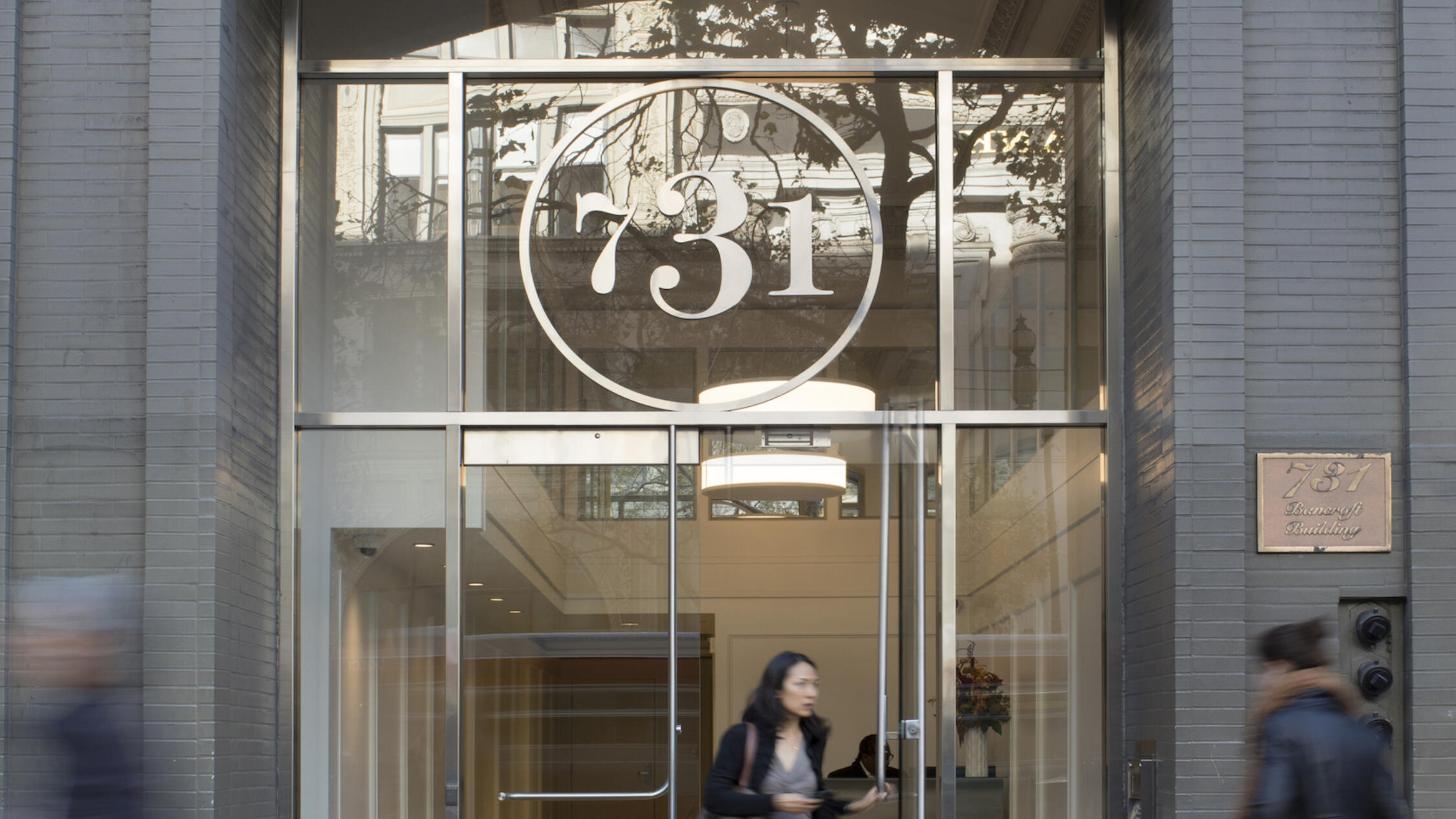 731 Market lobby entrance with pedestrians on sidewalk and visitor exiting door