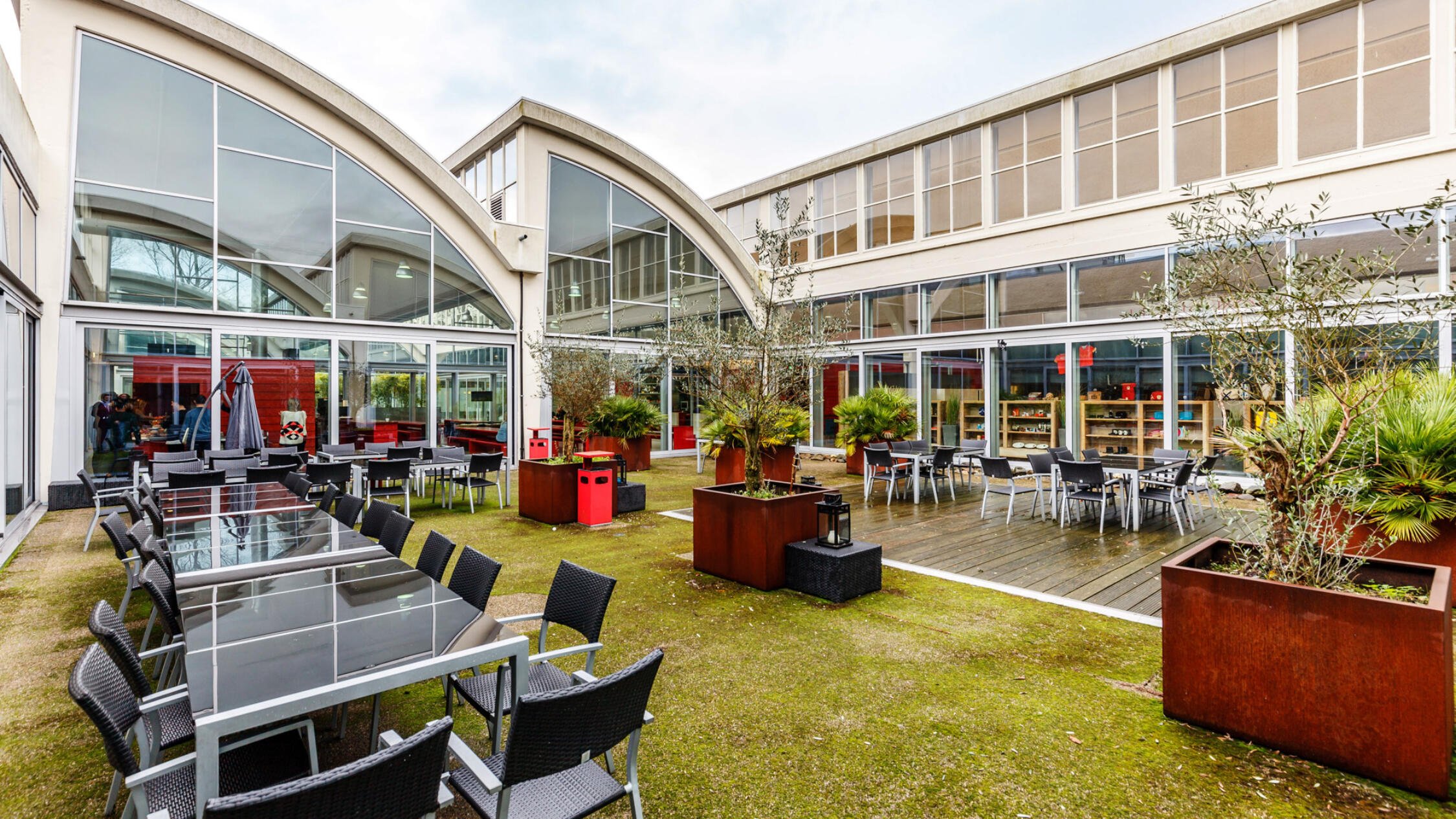 A Factorij exterior courtyard with tables and chairs, and trees in large planter pots