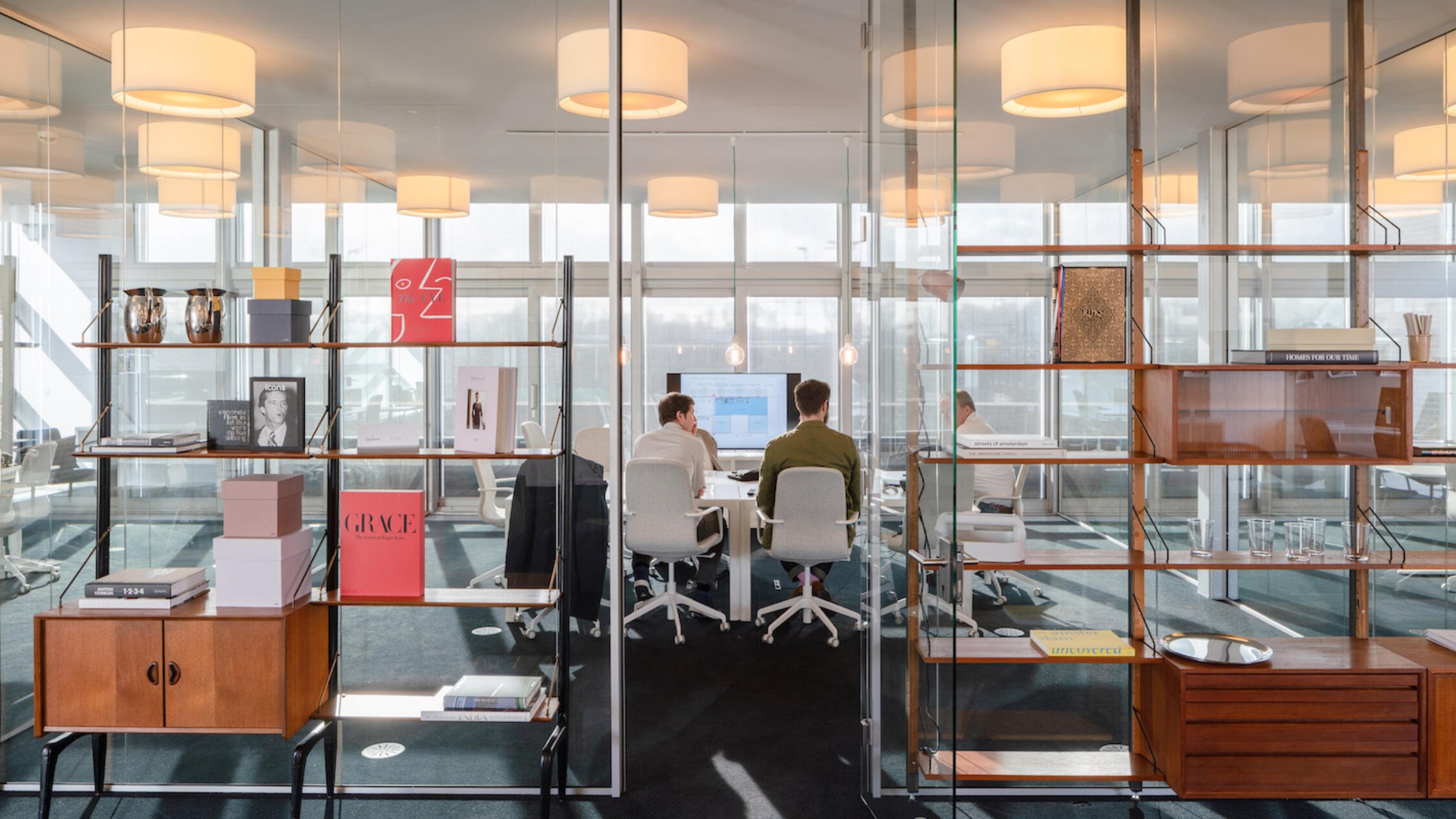 A Factorij interior office space with people working at desks framed by open bookcases