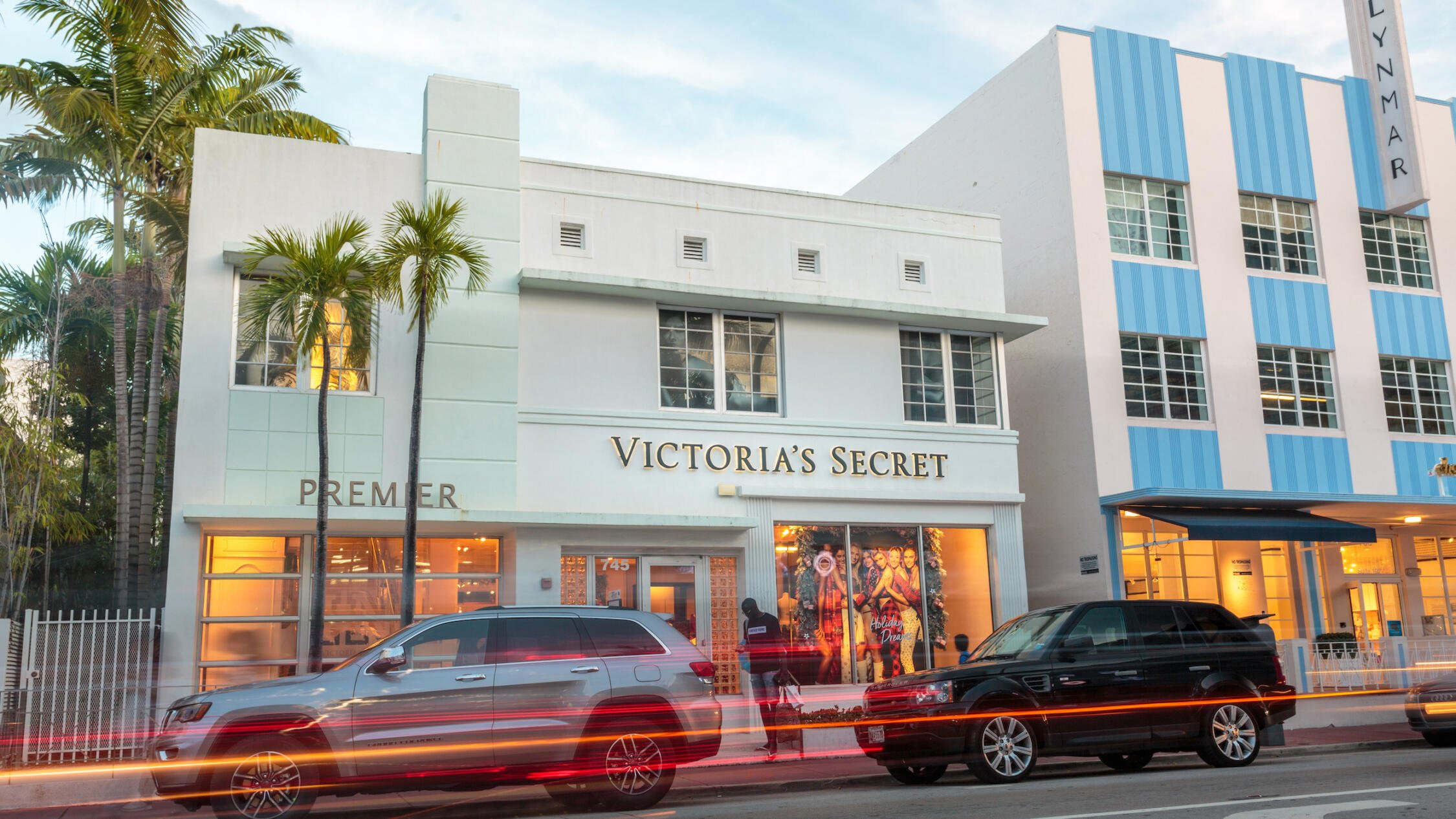 Collins Avenue Collection in the evening with cars moving past and palm trees on the left