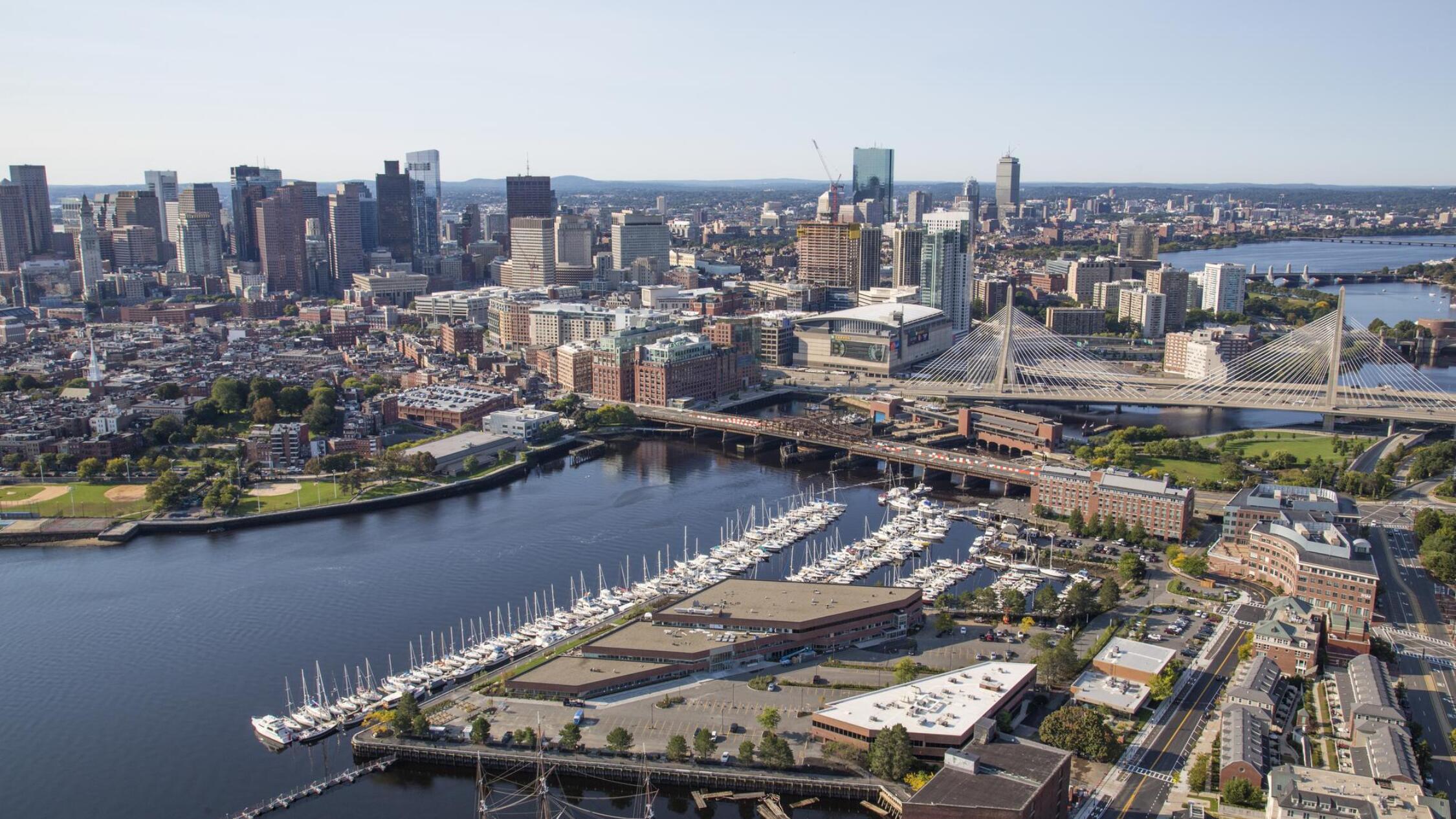 Aerial of Constitution Wharf building, marina, and river, with Boston skyline in background
