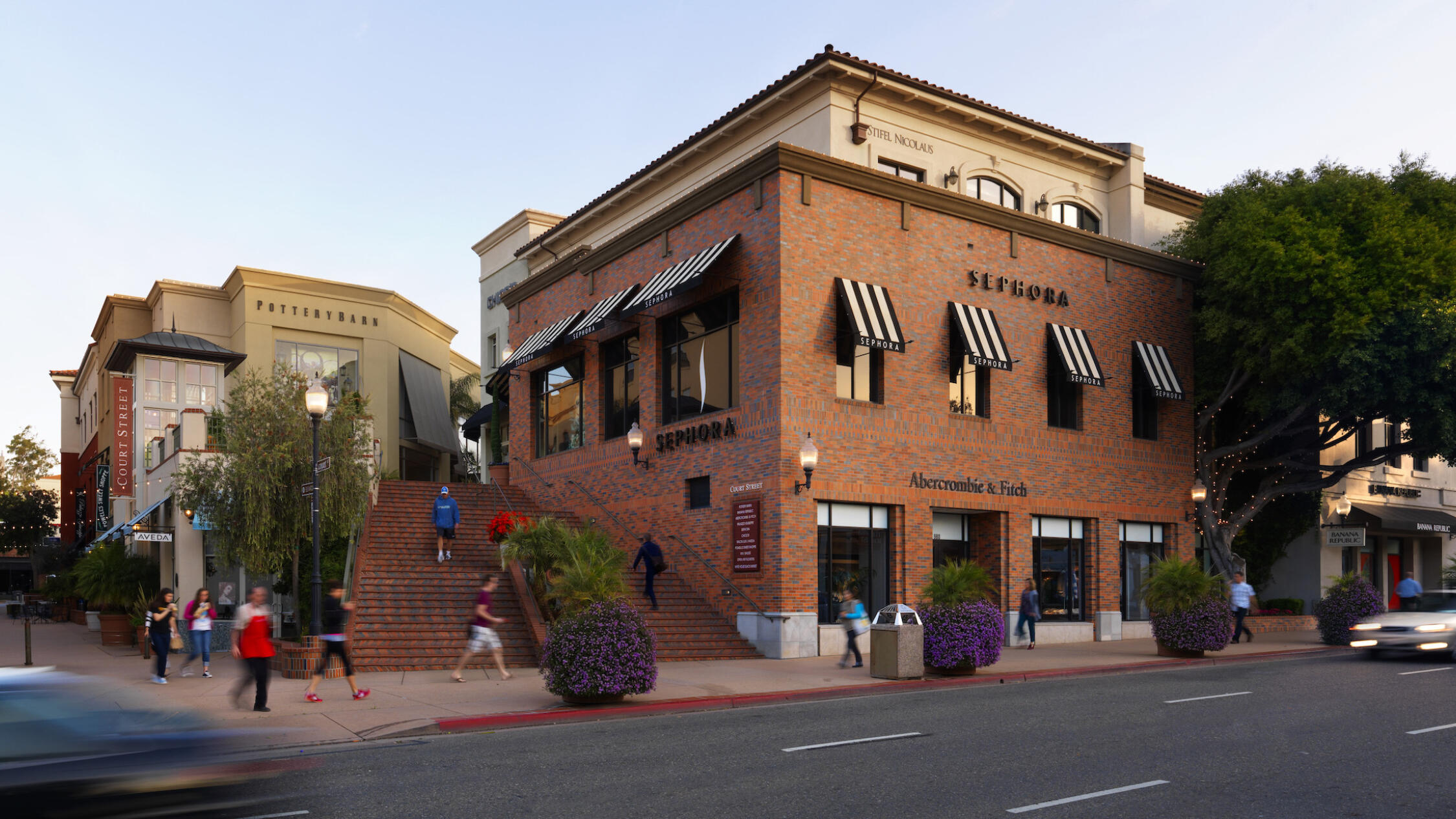 Street view of The San Luis Obispo Collection with people walking on the sidewalk and cars moving past