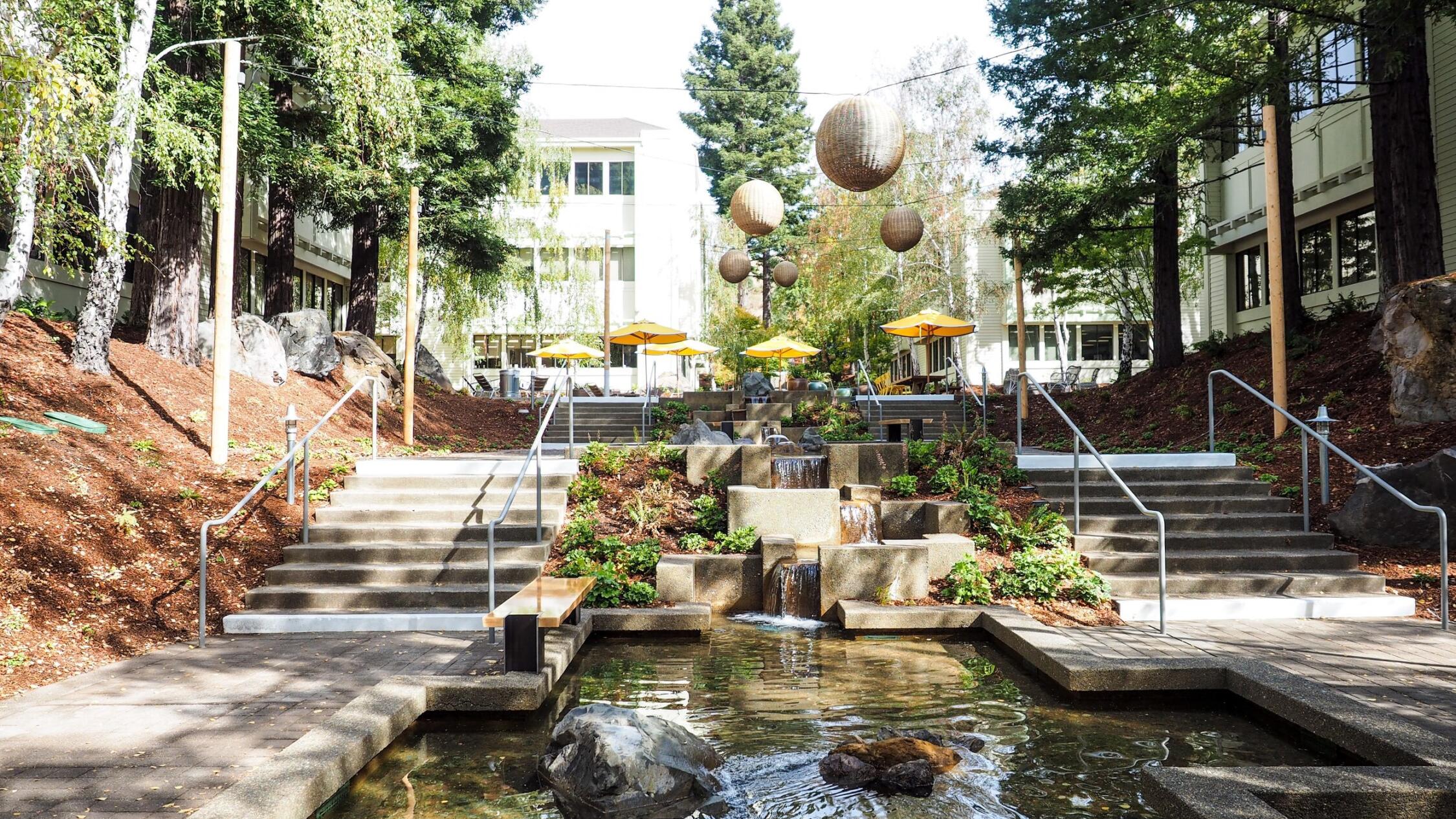 The courtyard at The Exchange at Larkspur Landing with large trees and water cascading into a reflecting pool