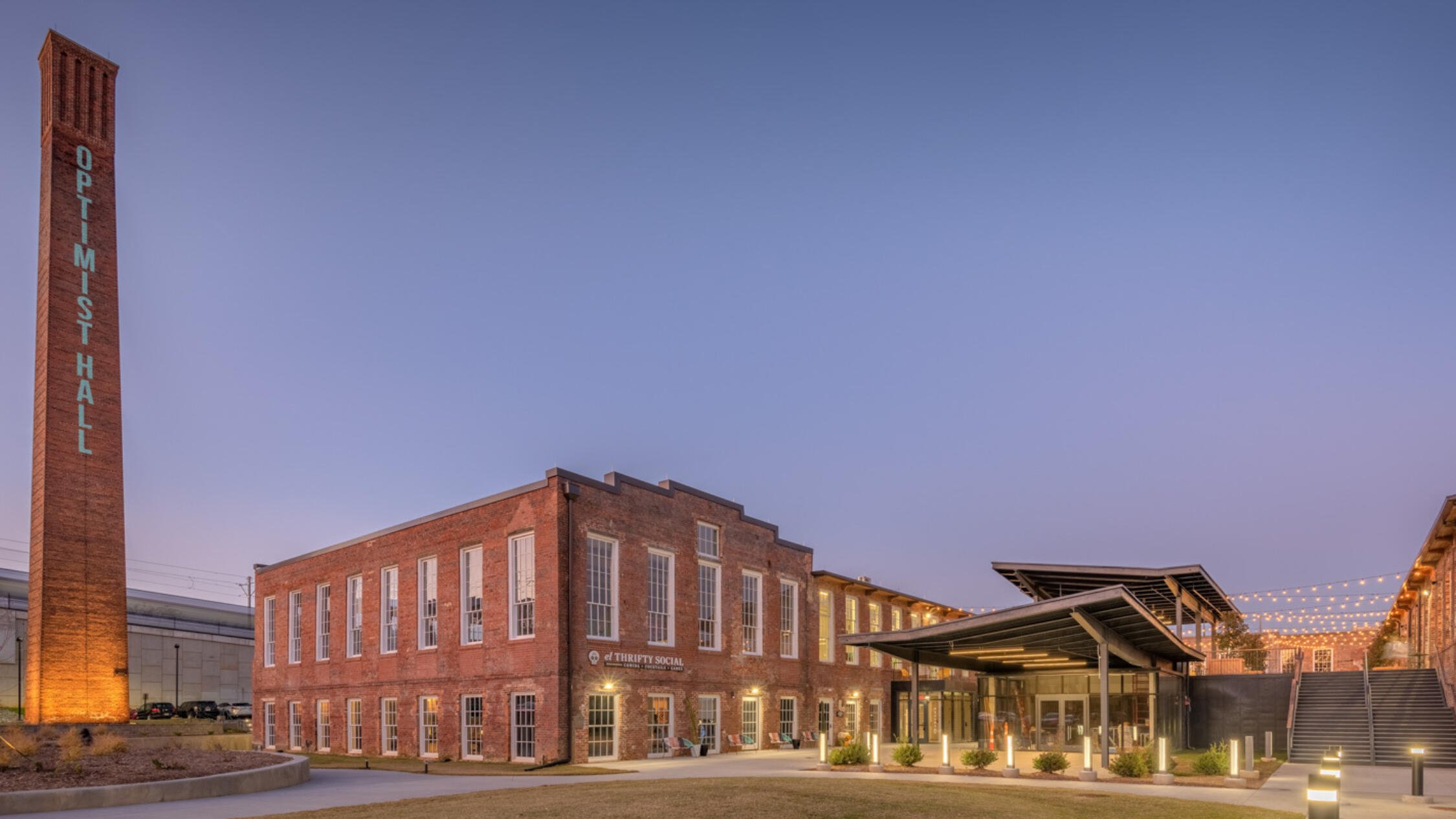 Optimist Hall facade, courtyard, and monument sign at dusk