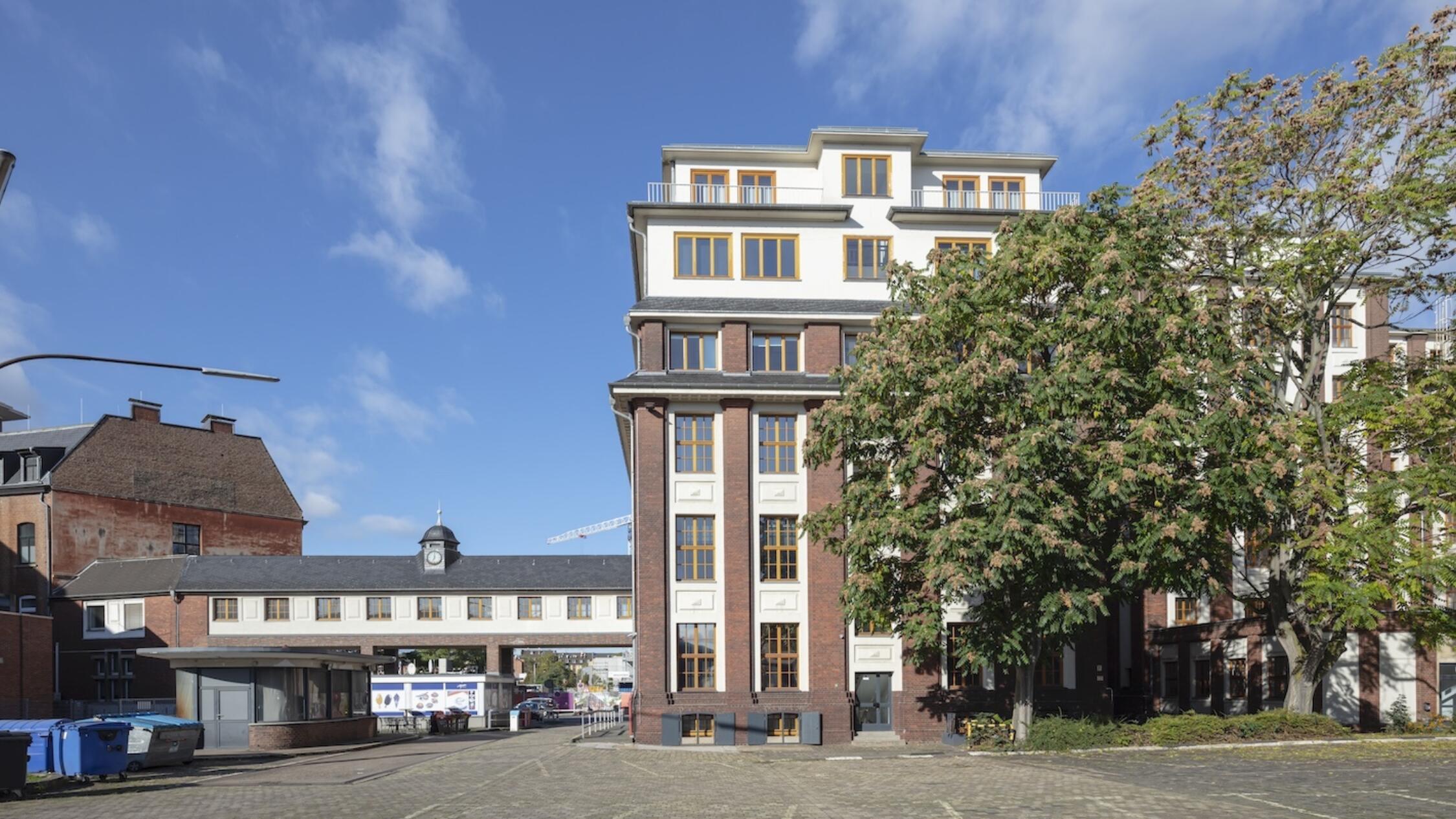 Schanzenstrasse facade with trees and parking lot in foreground