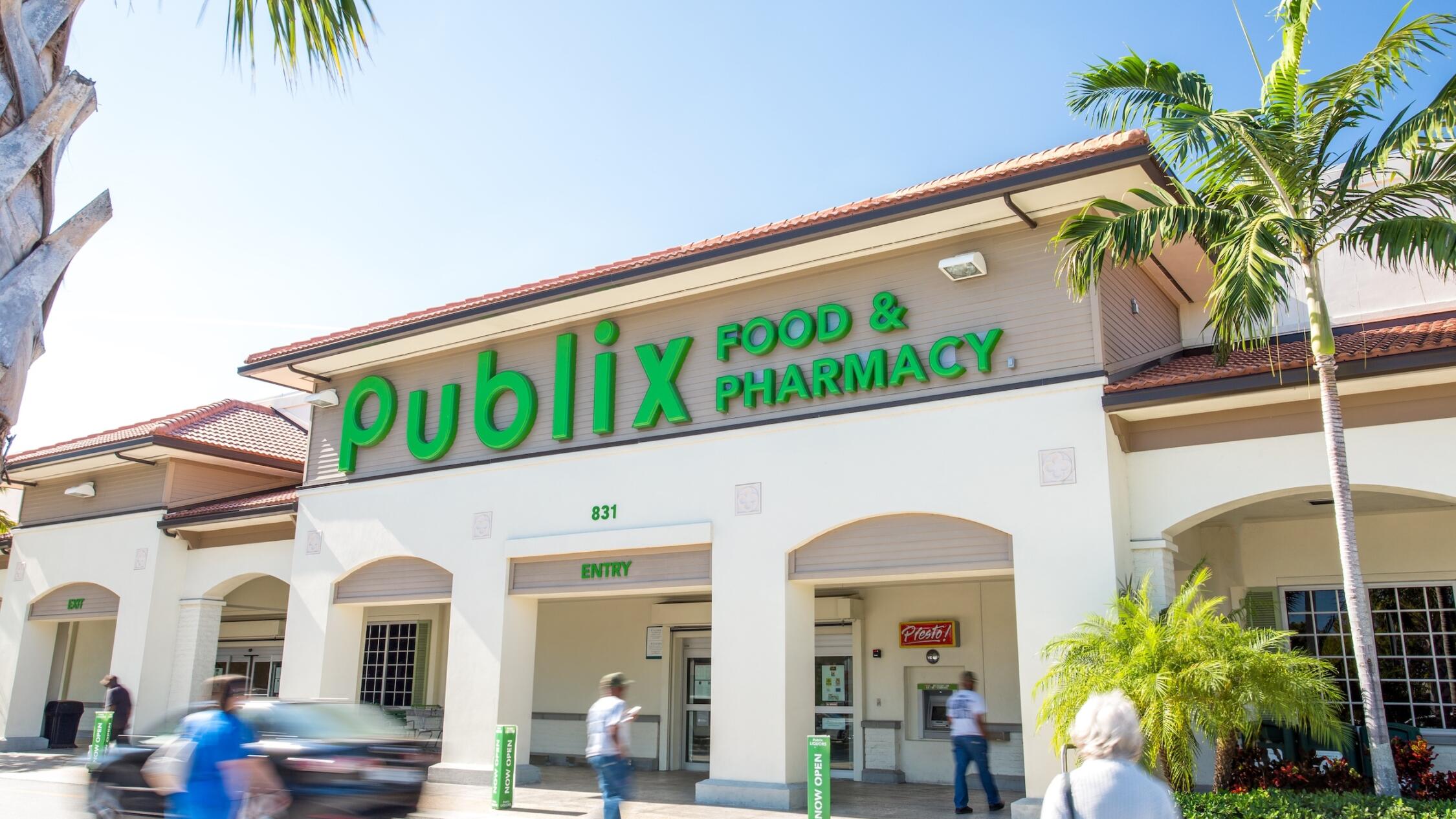 Exterior street level view of Publix grocery store at Village Commons with people and cars passing by