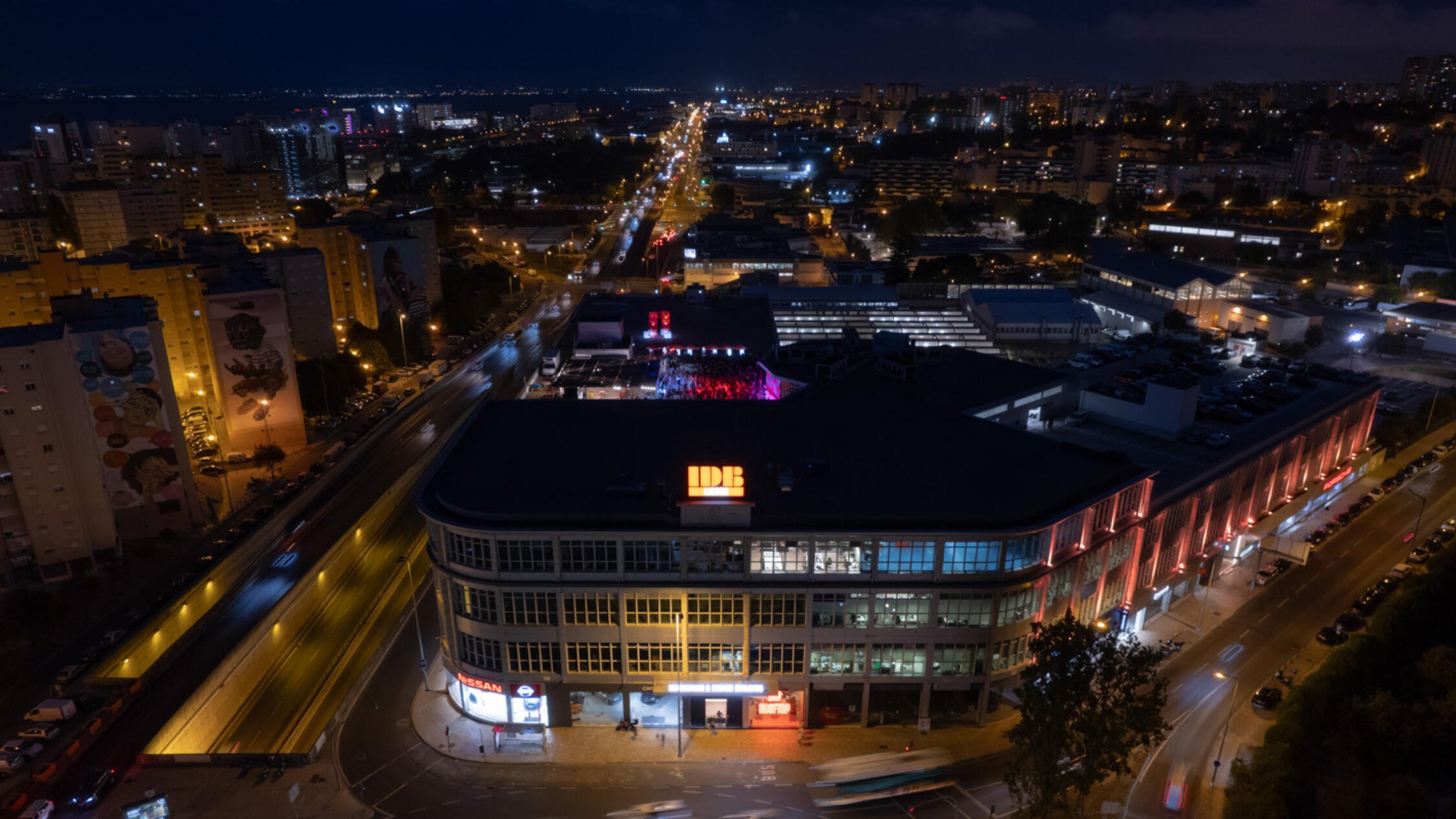 IDB Lisbon's building facade at night, with buildings and streets in background