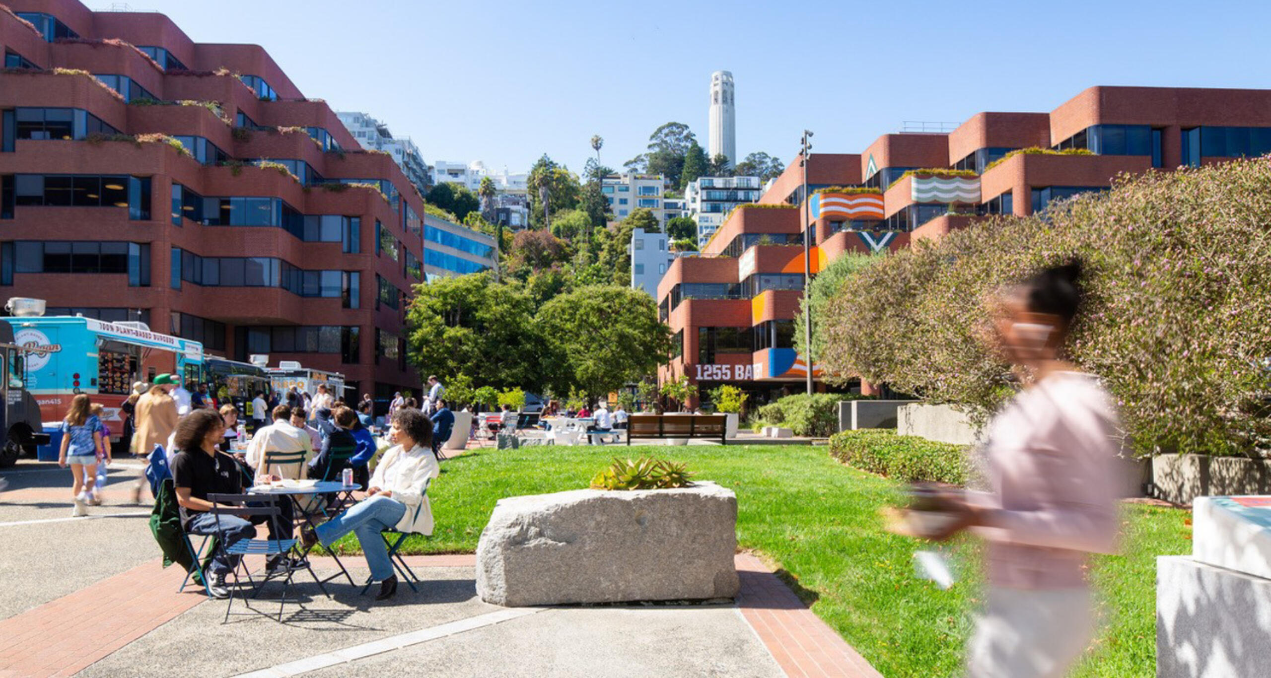 Levi's Plaza exterior with people in a sunny courtyard and Coit Tower in the background