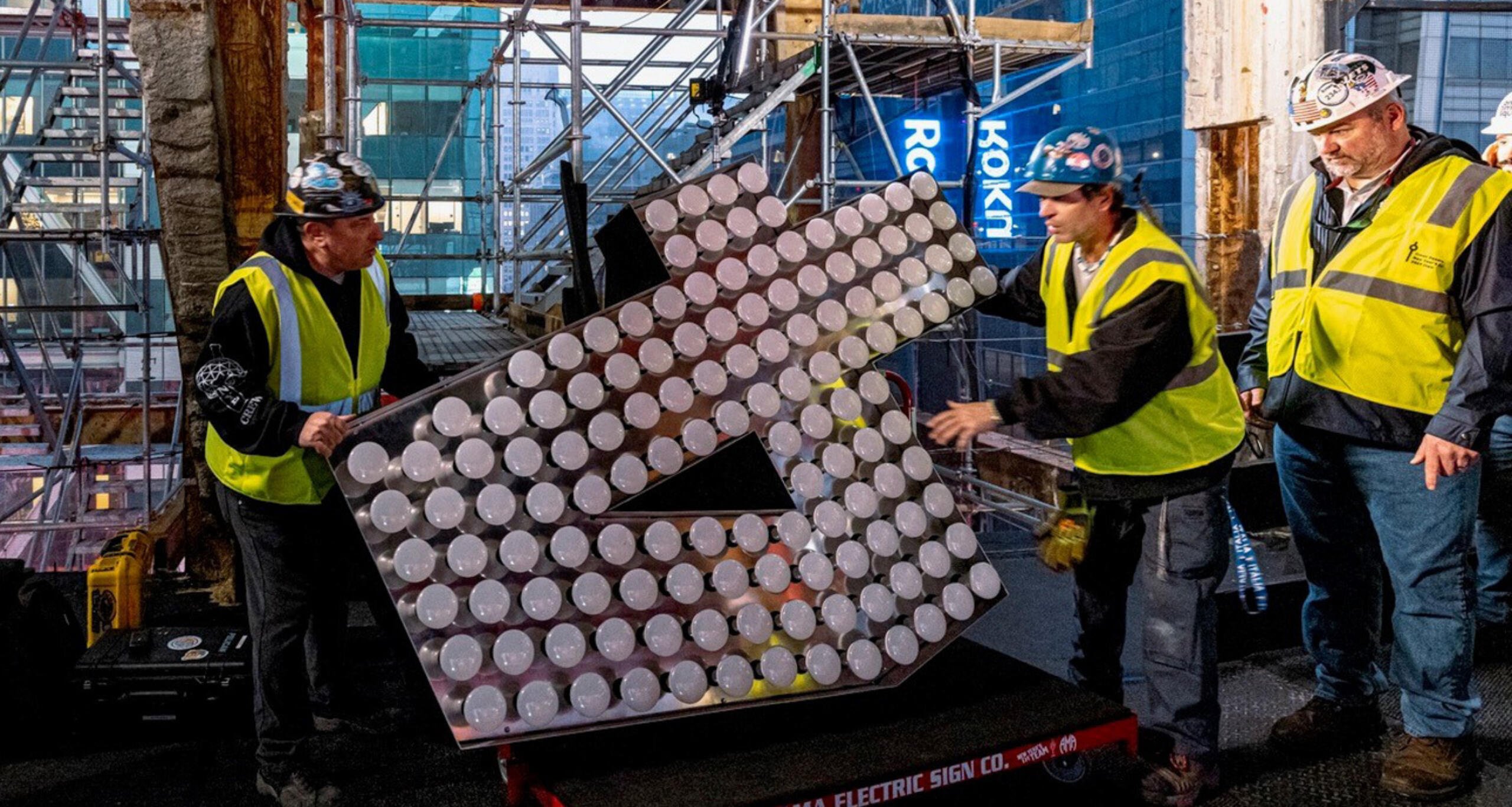 Construction workers moving a giant numeral 4 at One Times Square