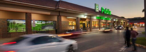 Country Club Plaza exterior of grocery store at dusk with cars and pedestrians in driveway