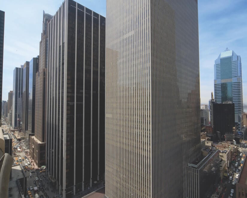 Wide exterior shot of 1211 Avenue of the Americas with traffic passing through on the streets below