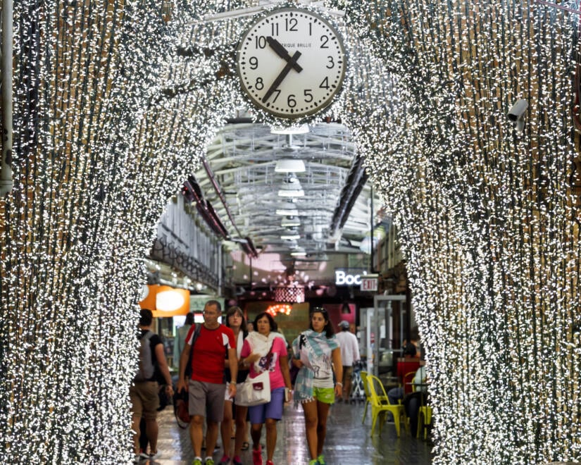 People walk through the archway at Chelsea Market which is adorned with string lights for the holidays.