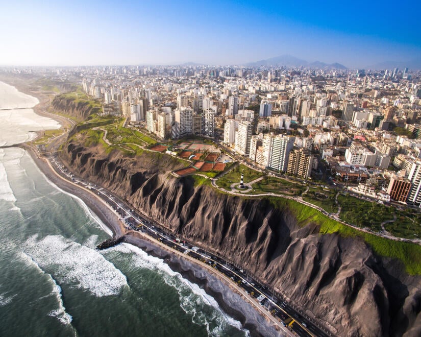 Aerial view of city skyline perched on rocky cliff above ocean