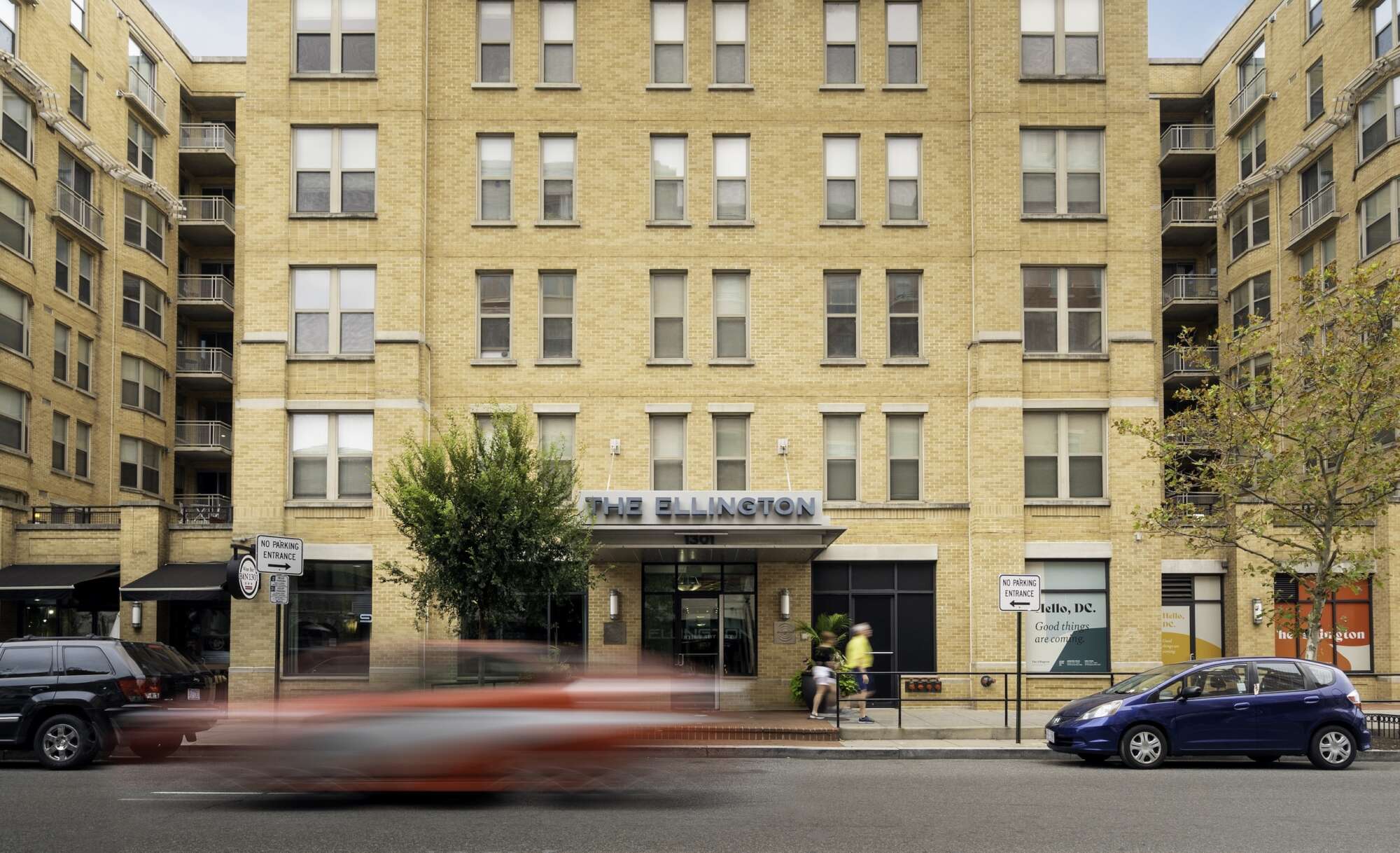 Street level exterior of The Ellington with a red Washington D.C. taxi driving past