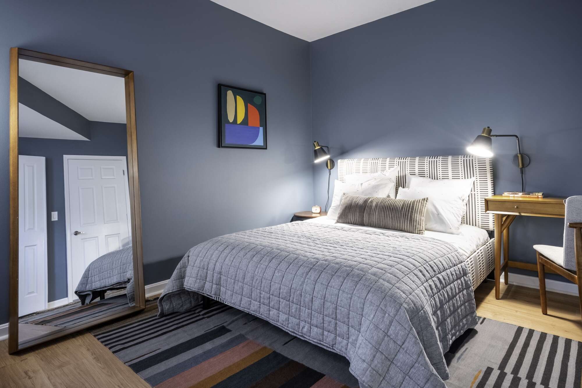 Bedroom of a model apartment at The Ellington with blue walls and a large bed