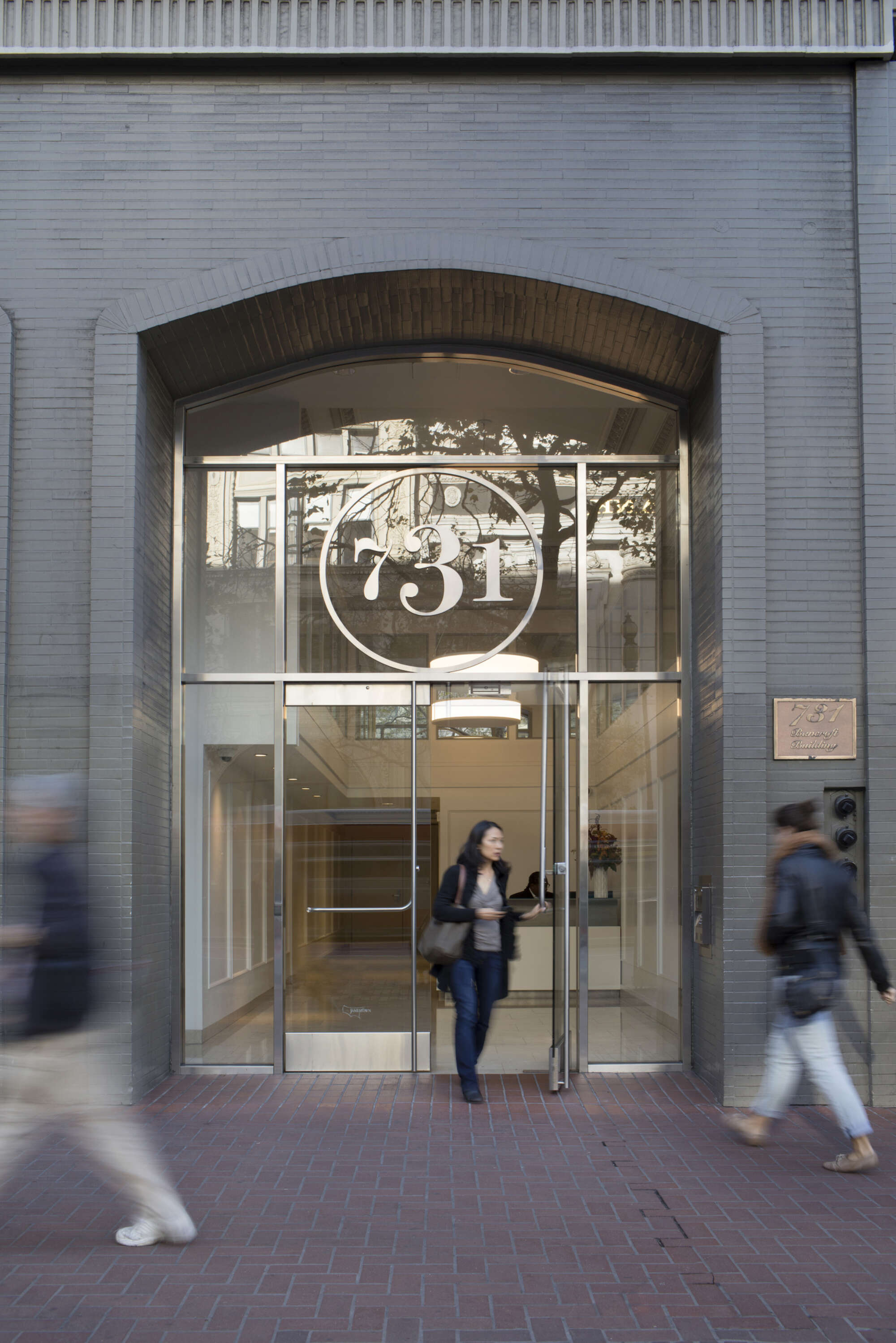 731 Market lobby entrance with pedestrians on sidewalk and visitor exiting door