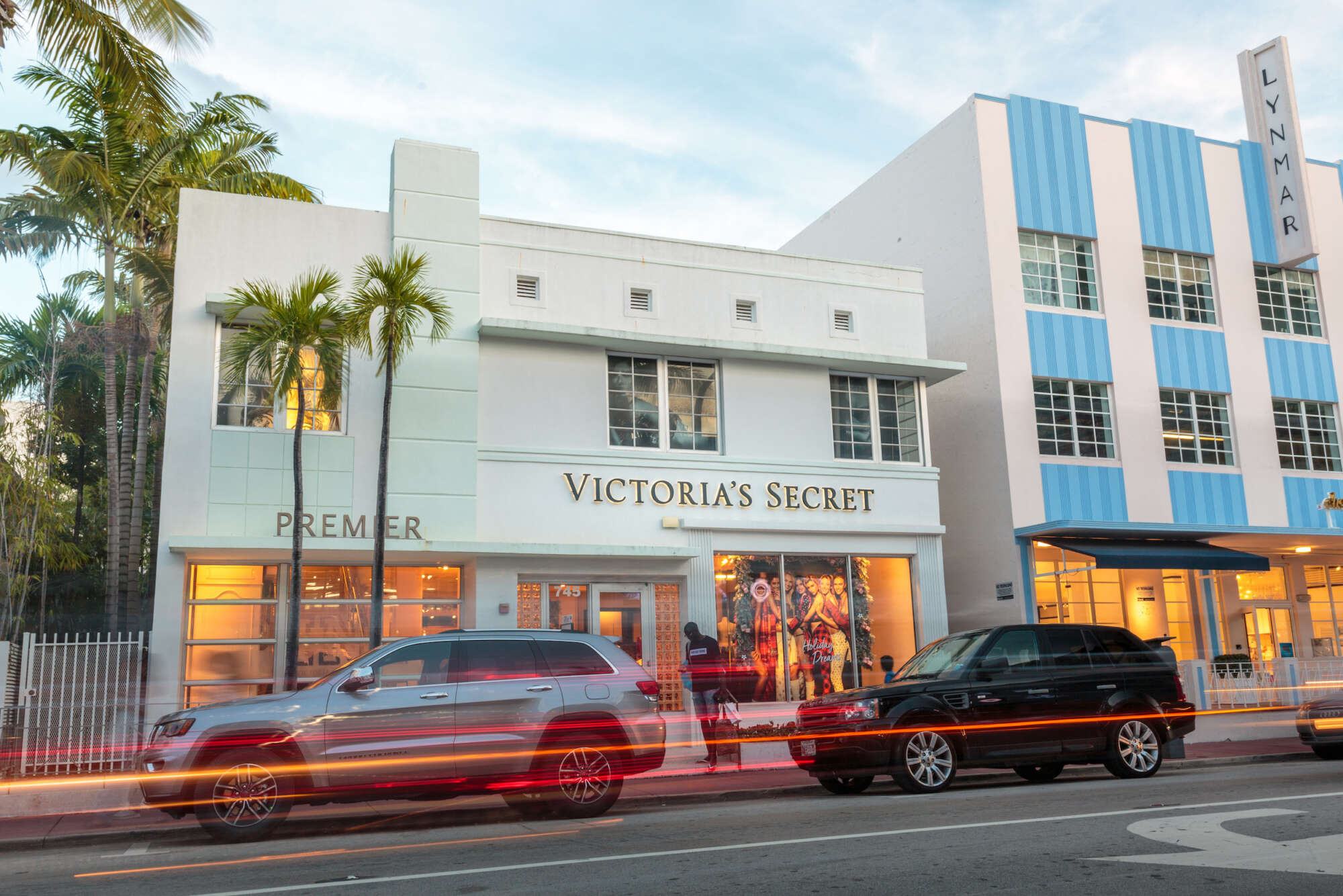 Collins Avenue Collection in the evening with cars moving past and palm trees on the left