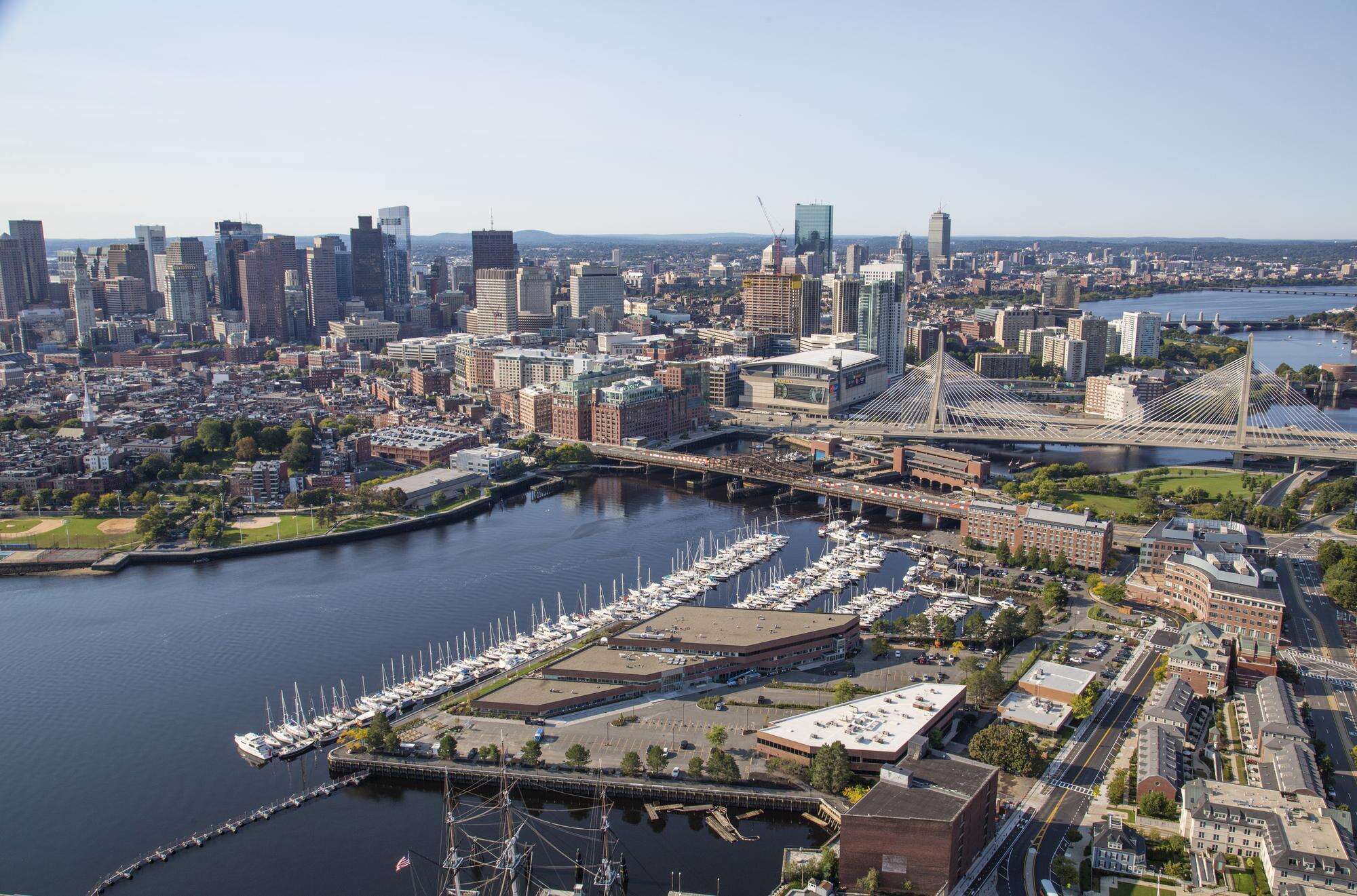 Aerial of Constitution Wharf building, marina, and river, with Boston skyline in background