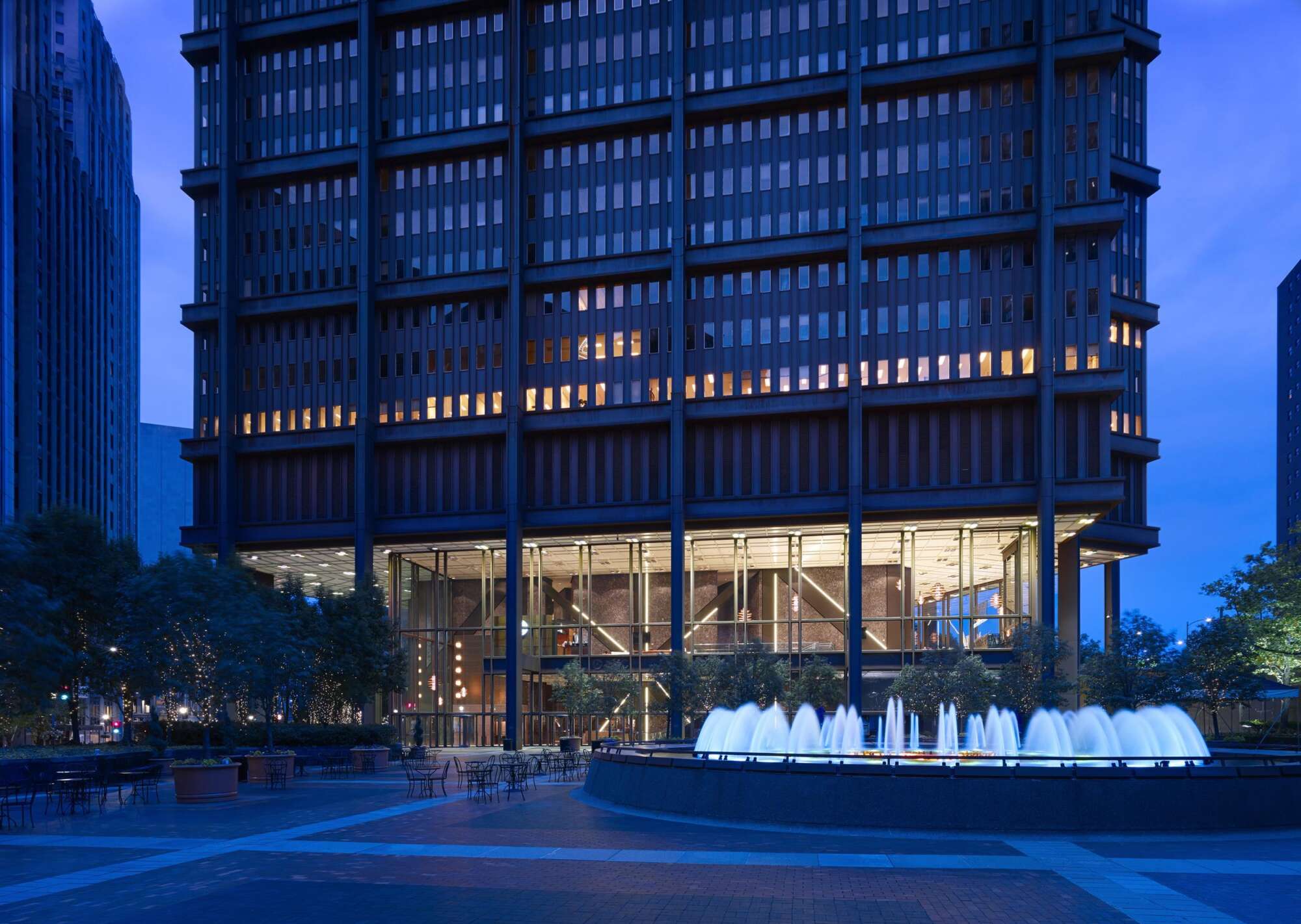 Ground level exterior view of the U.S. Steel Tower at night with a large fountain in the foreground