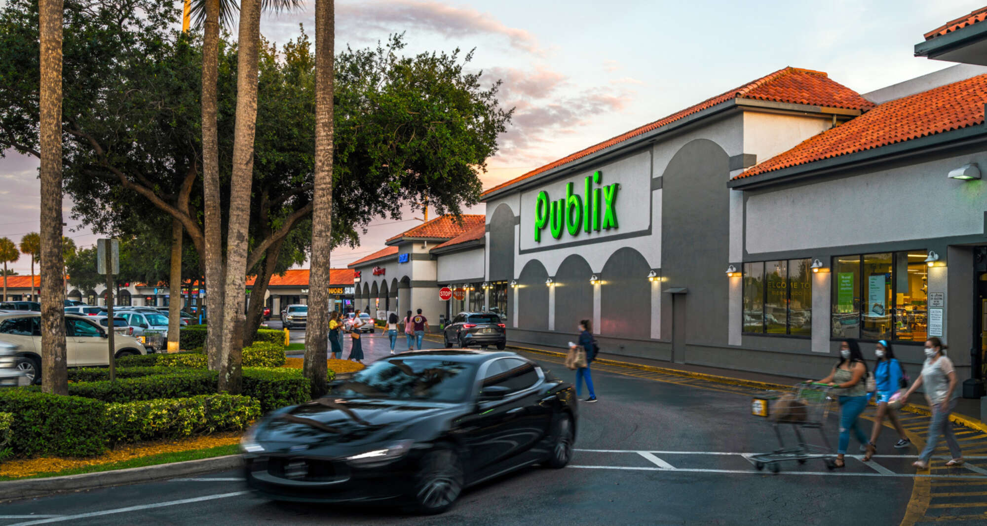 Grocery-anchored shopping center with Publix facade and pedestrians and cars on driveway